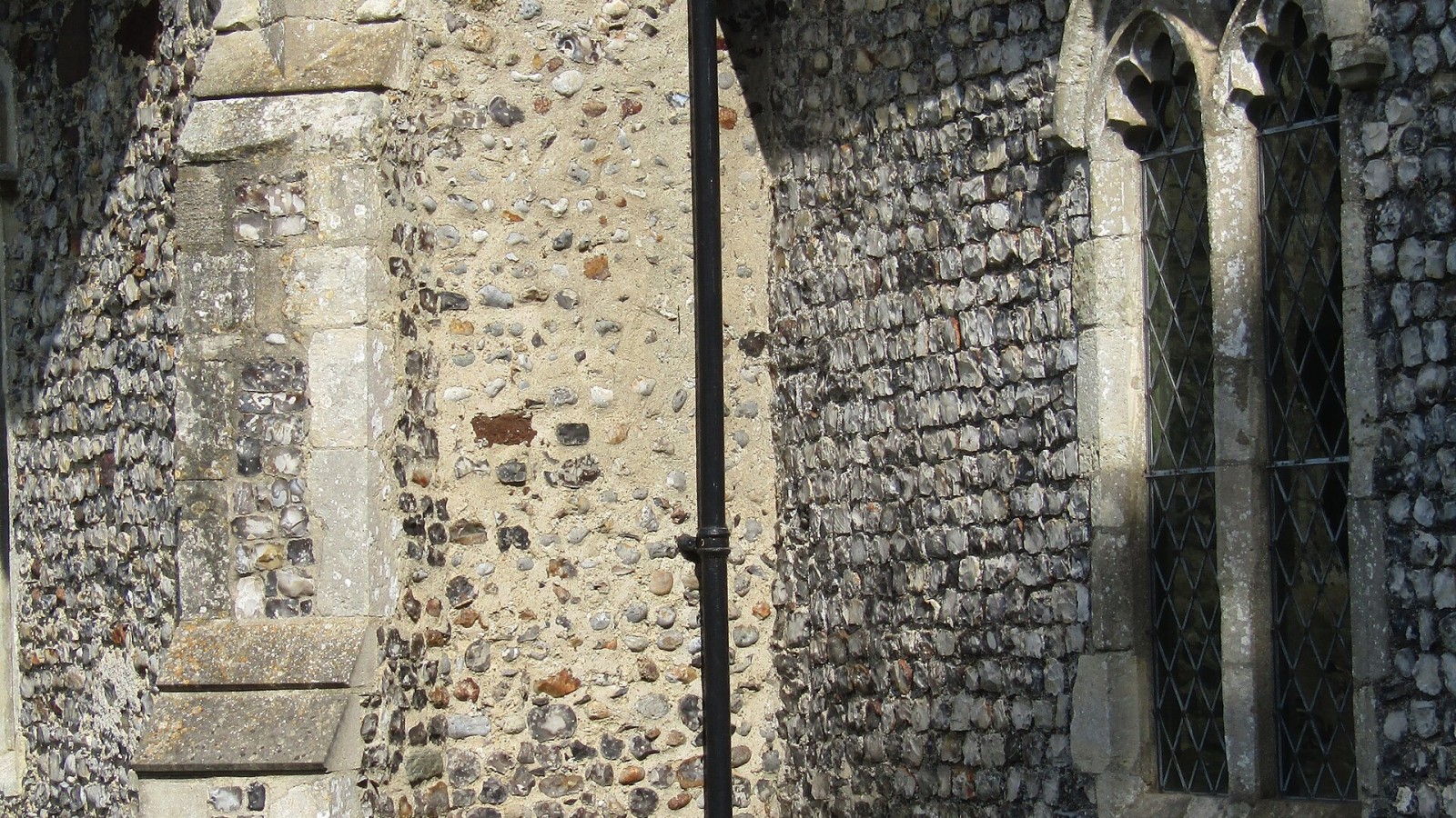 A Buttress and gutter downpipe on the south wall of the parish church of All Saints within the village of Edingthorpe, Norfolk