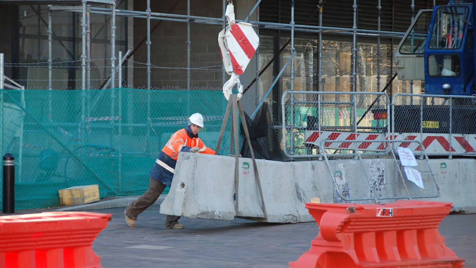Construction worker moving a concrete barrier.