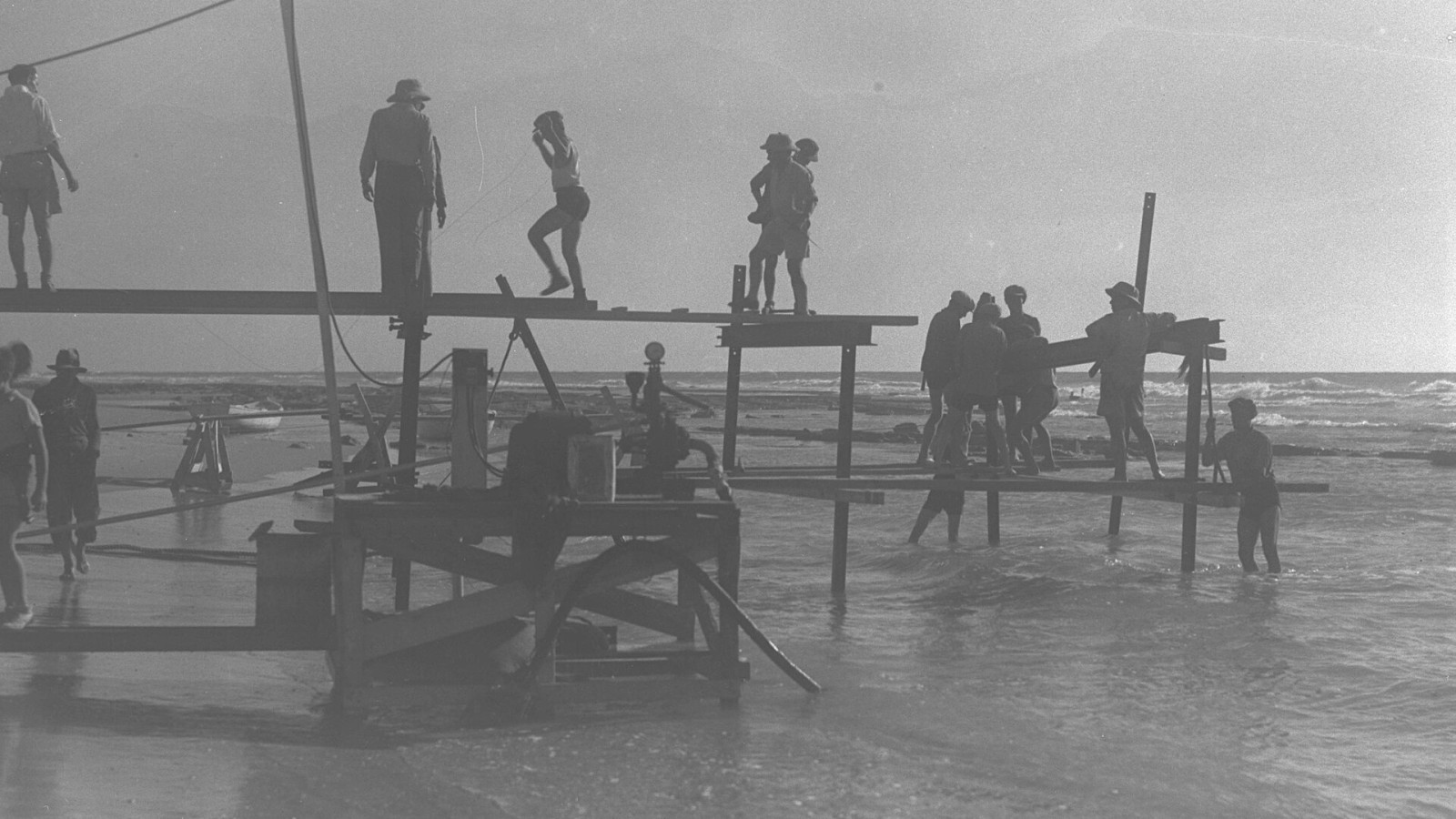 CONSTRUCTION WORKERS BUILDING A LANDING STAGE ON THE SITE OF THE PORT OF TEL AVIV. פועלים בונים רציף צף, באתר בו יוקם נמל תל אביב.