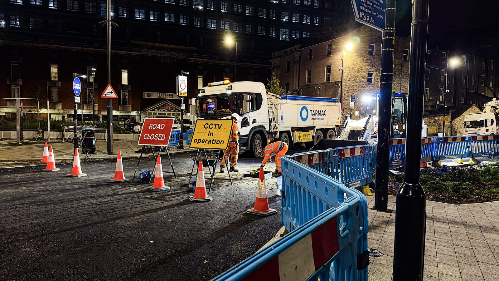 This night time photograph shows road repair work taking place on Globe Lane during improvements to Chatham Waterfront bus station in Chatham, Kent, England, capturing an active construction site with several vehicles an