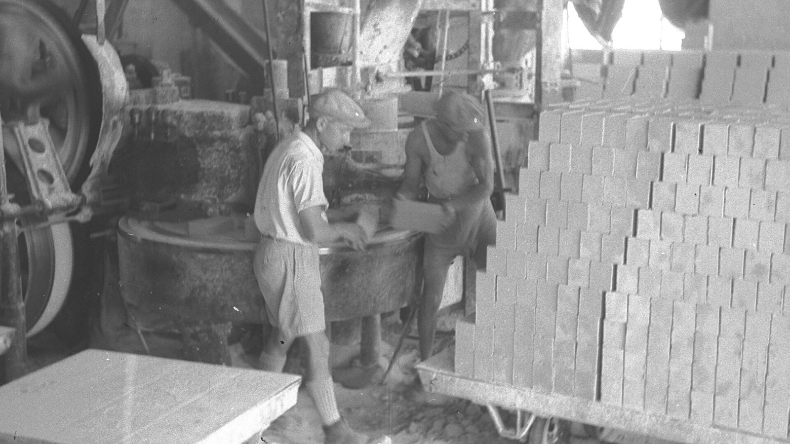 WORKERS LOADING BUILDING BRICKS ON A CART IN A TEL AVIV FACTORY. מפעל ללבני בנייה בתל אביב. בצילום, פועלים מעמיסים לבנים על עגלה.