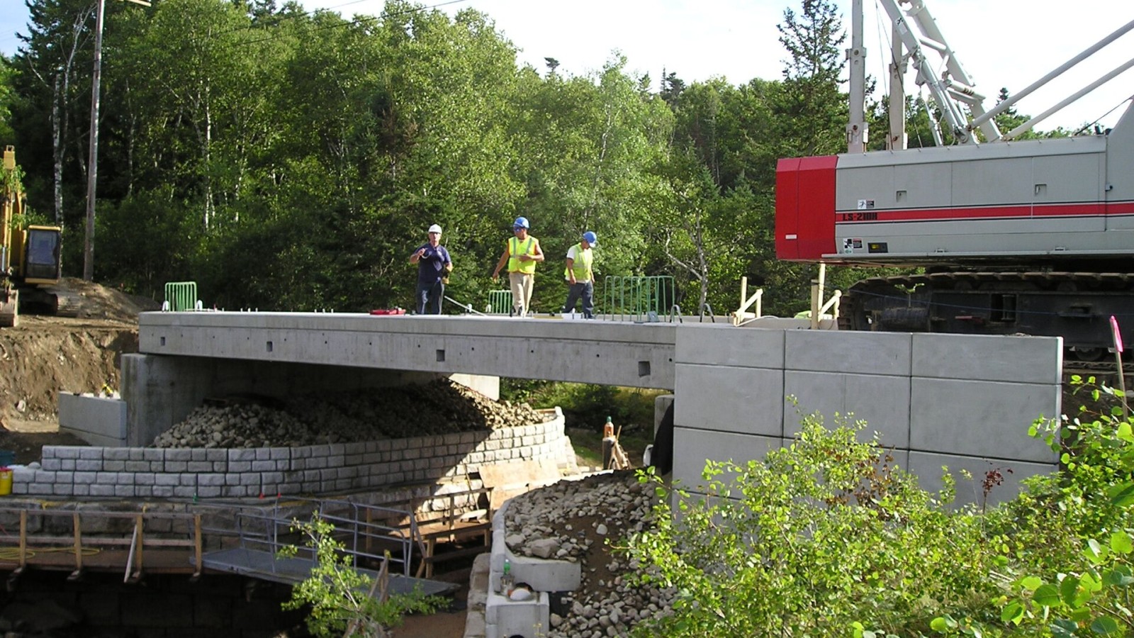 Looking westbound shows the precast concrete backwall, the precast, segmental retaining wall panels, and the post-tensioning duct pockets in the fascia beam work that is part of a FHWA, Highways for LIFE supported projec