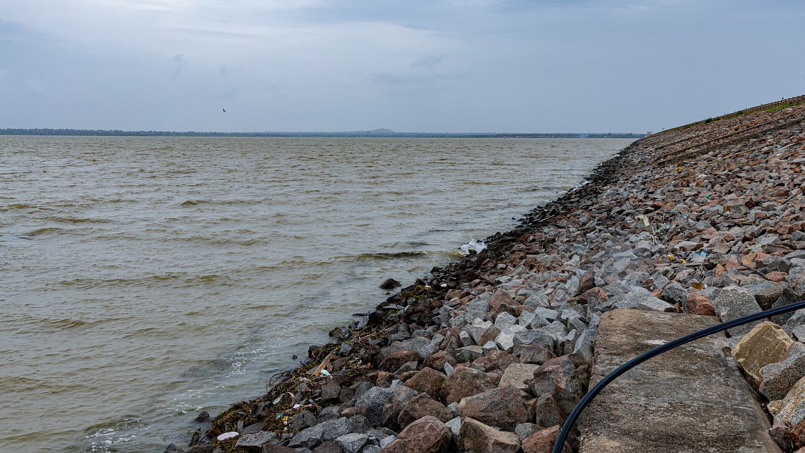 Upstream (reservoir) side of Narayanpur Dam (Basava Sagar Dam) on the Krishna River in Karnataka, India. The image shows the water storage area behind the dam and the sloped embankment protected with riprap (rock armour)