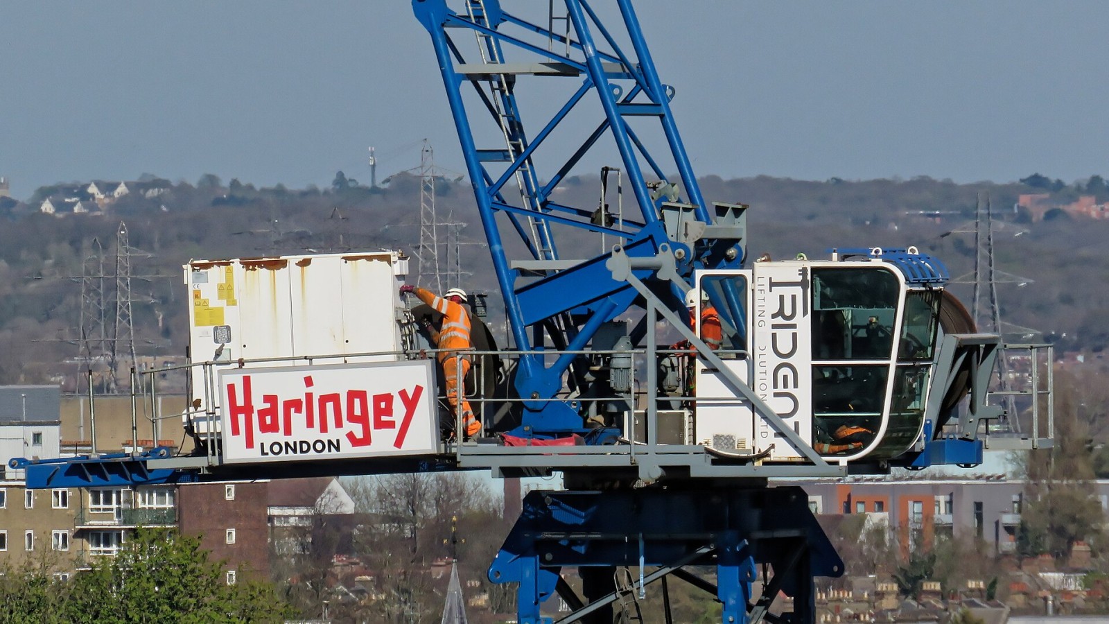 Building construction crane with men at work, at Moira Close, in the Borough of Haringey in London, England, in April 2025.Wikimedia (2025) makes it difficult to immediately view photo groups related to this image. To se