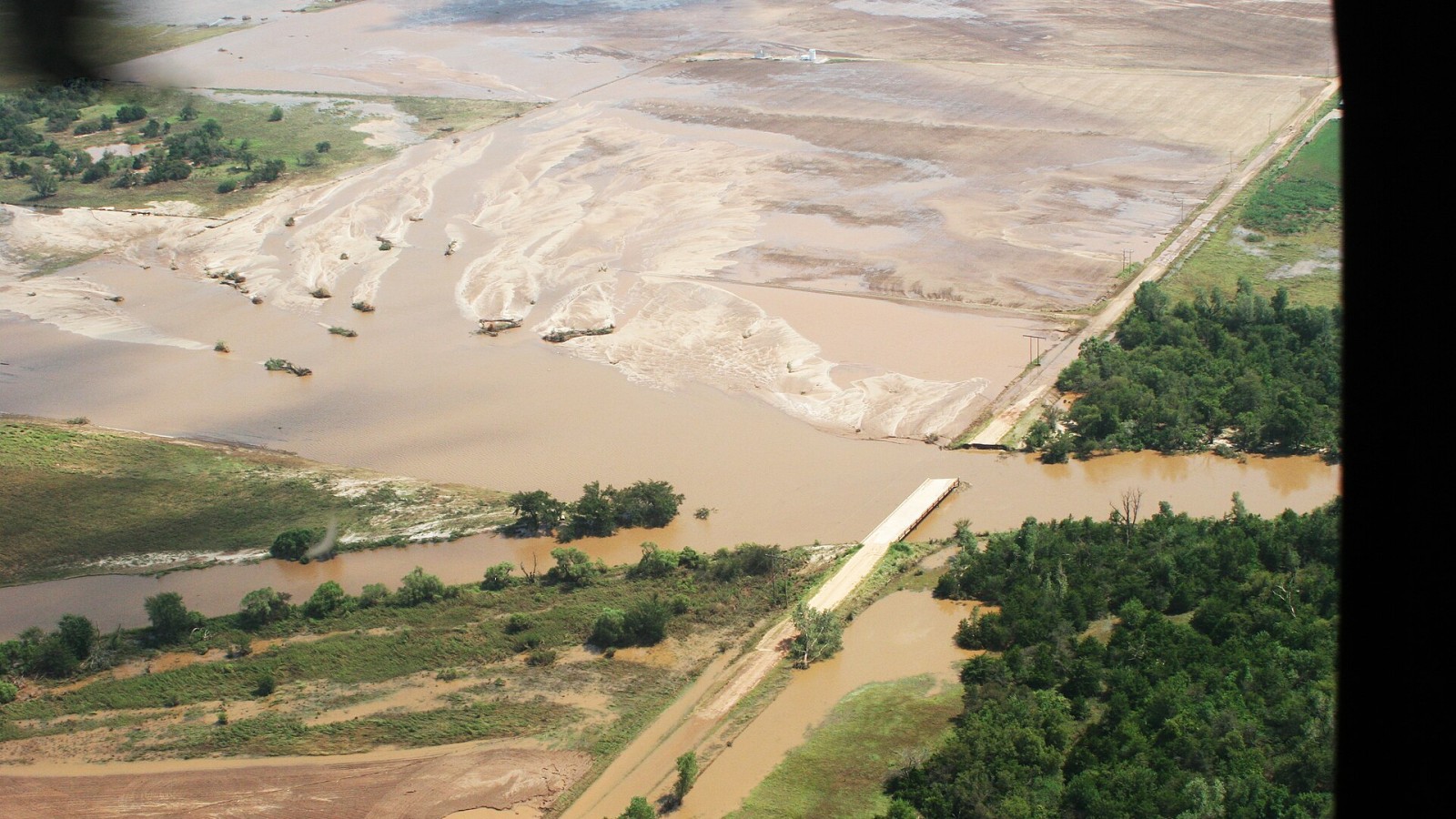 Kingfisher, OK, August 20, 2007 -- Aerial of a damaged bridge and flooded farm land. Access to farms and homes were cut off due to collapsed roads and bridges in rural Grady County, forcing families to find another route