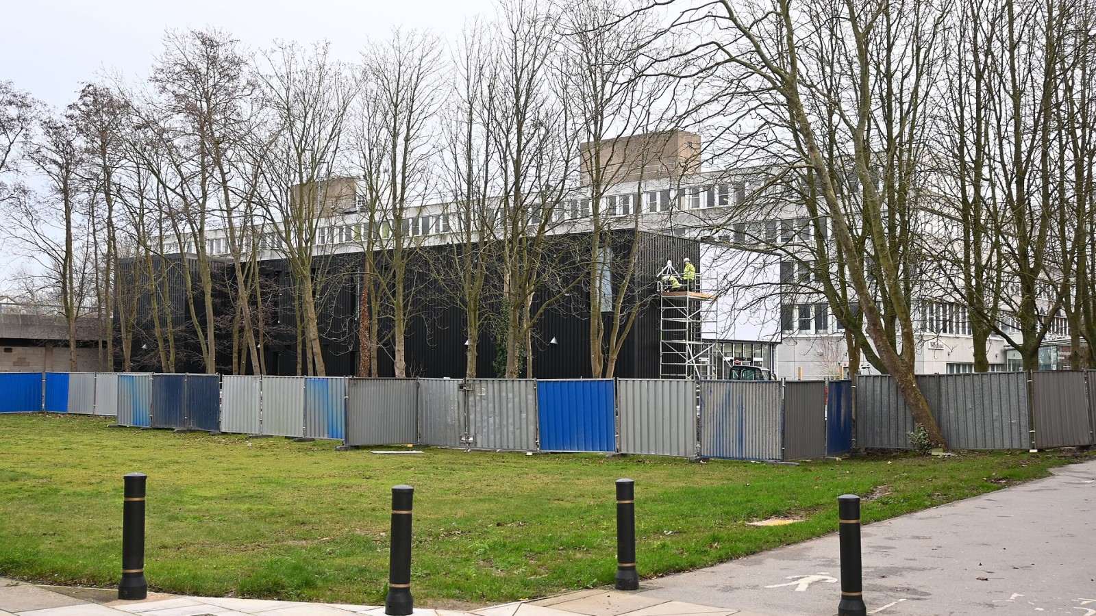 Another angle of construction work at the University of Hull's Centre of Excellence for Data Science, Al, and Modelling (DAIM) building, with construction workers unveiling the signage for the building