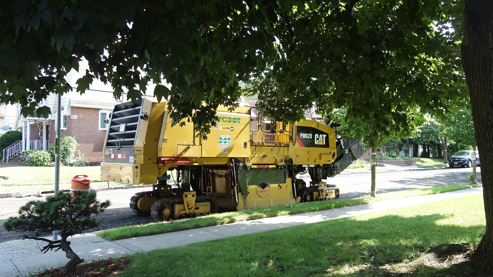 Looking at the repaving of 81st Avenue, at the intersection of 81st Avenue and 169th Street in Hillcrest, Queens. In a matter of four hours, the road has been successfully stripped of asphalt. Pictured is a Caterpillar P