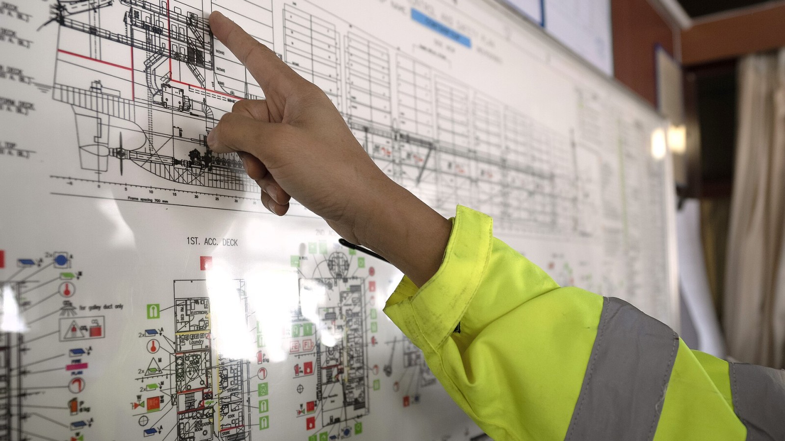 The engineer of a cargo ship points to deck chart as he assists a U.S. Border Patrol Search, Trauma and Rescue (BORSTAR) agent with lockout/tagout procedures on the bridge. The lockout/tagout process ensures that propell