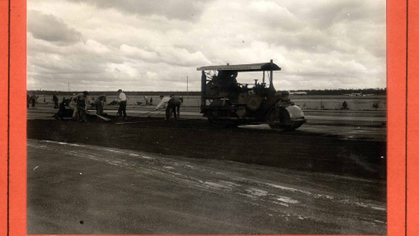 German workers spread asphalt with rakes in preparation of rolling operations [at Tegel Airfield].
