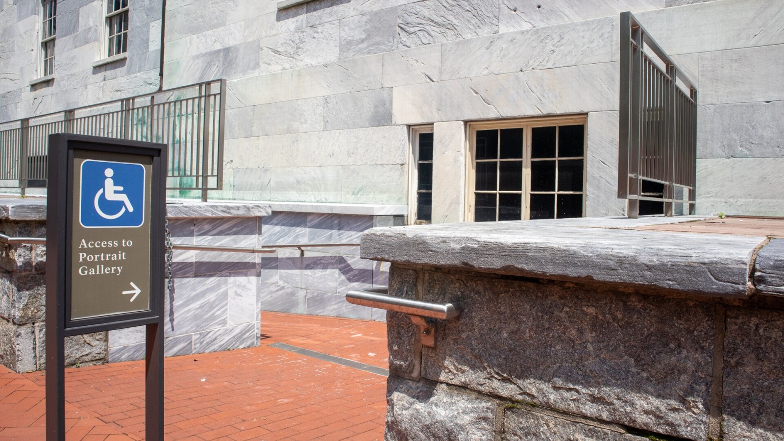A wheelchair accessible entrance sign stands at the top of a ramp. Visitors with mobility challenges may wish to enter the building from the west side ramp. Keywords: Second Bank of the United States; Portrait Gallery; a