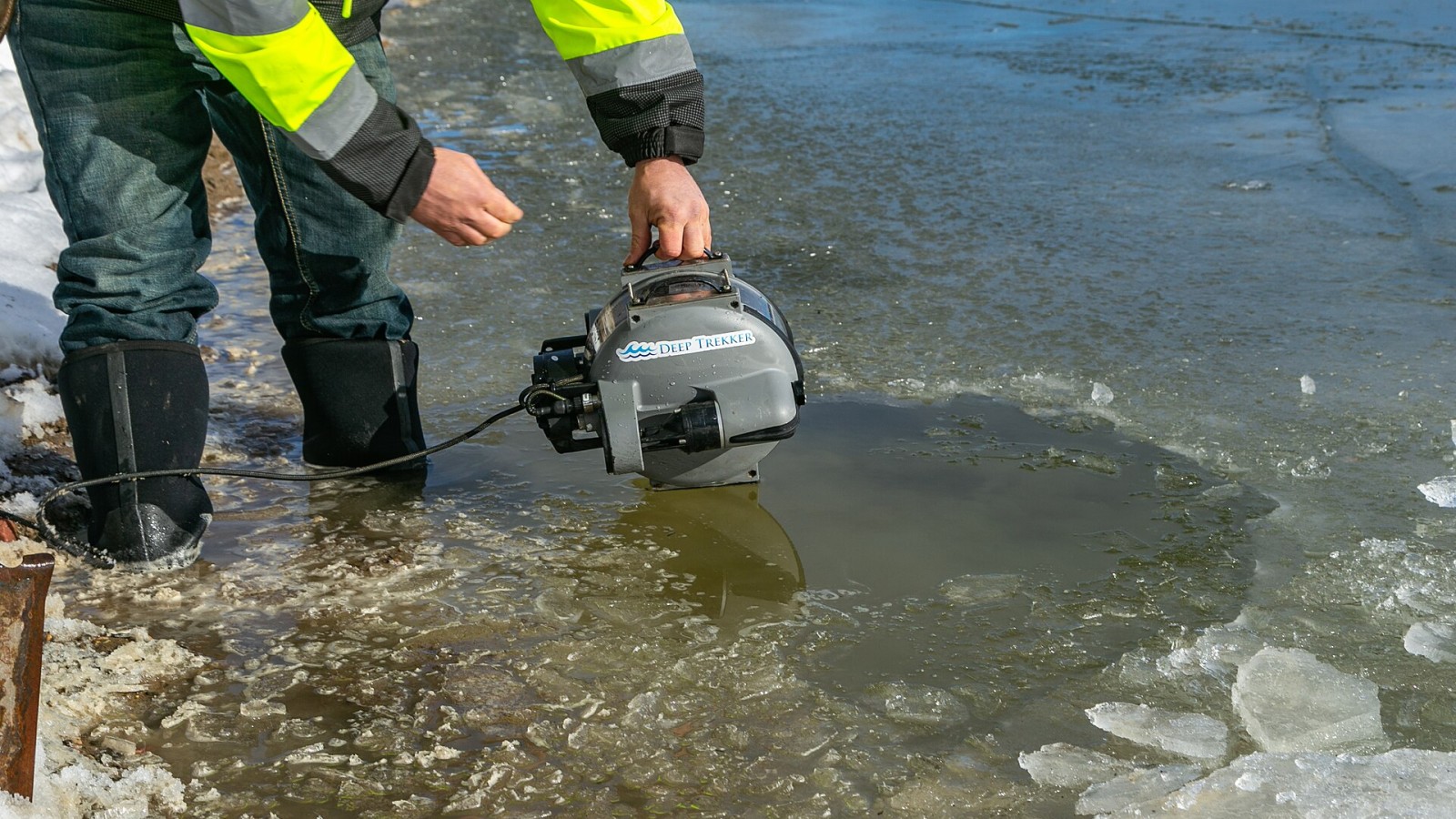 A small inspection ROV is deployed under the ice in reservoir by a water utility maintenance technician.