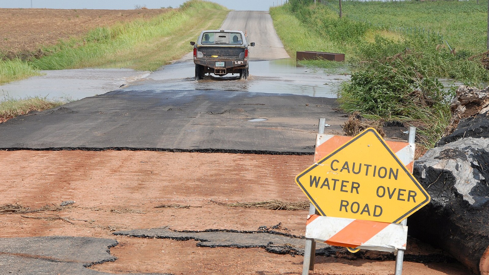 El Reno, OK, August 19, 2007 -- A truck drives past a "Caution Water Over Road" sign. Many flooded roads were damaged and must be repaired. FEMA has a Public Assistance program to help local governments recover costs for