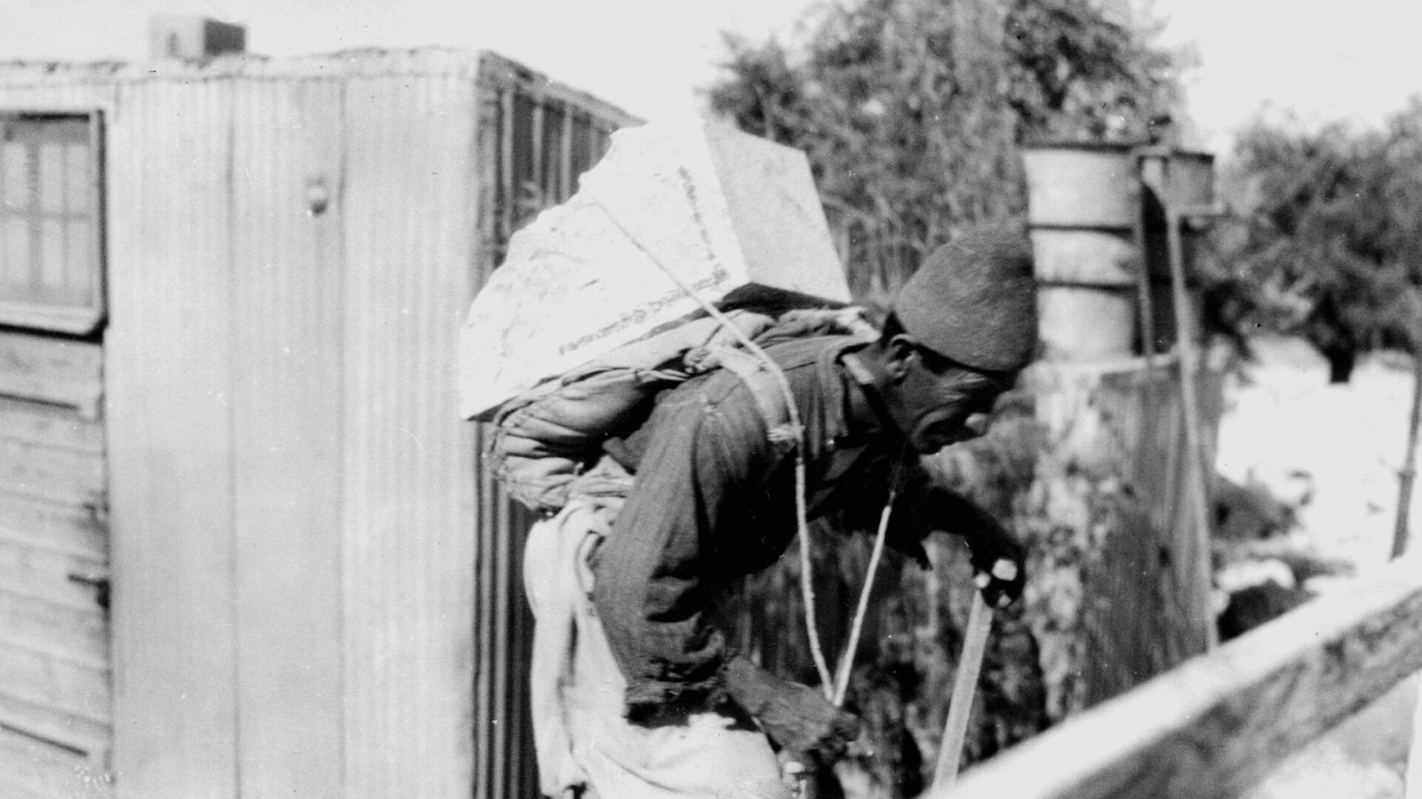AN ARAB CONSTRUCTION WORKER CARRYING A CORNERSTONE FOR THE Y.M.C.A. BUILDING IN JERUSALEM. פועל בנייה ערבי סוחב על גבו אבן פינה לבניית בניין ימק"א בירושלים.