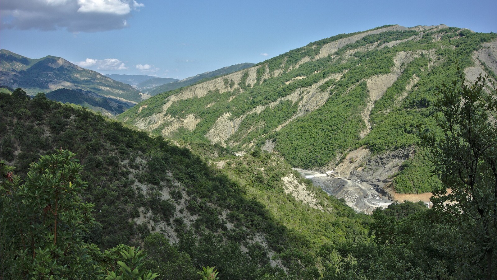 River Lengarica with wooded hills and construction site for a dam for a hydroelectric power plant