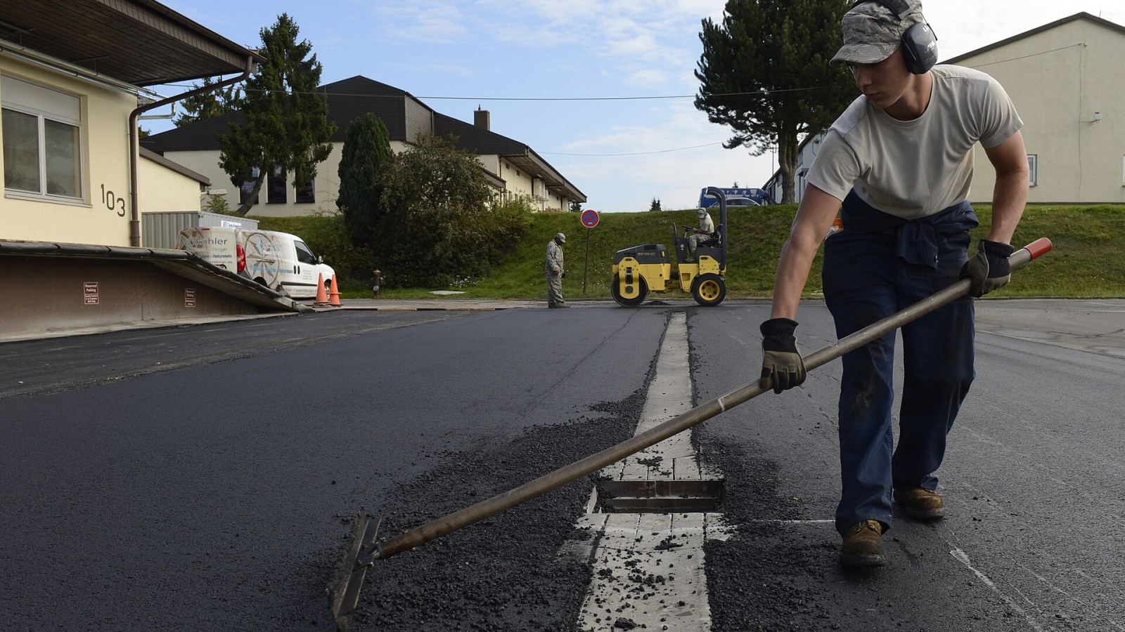 Road worker assists in the construction and maintenance of an asphalt concrete paved road.